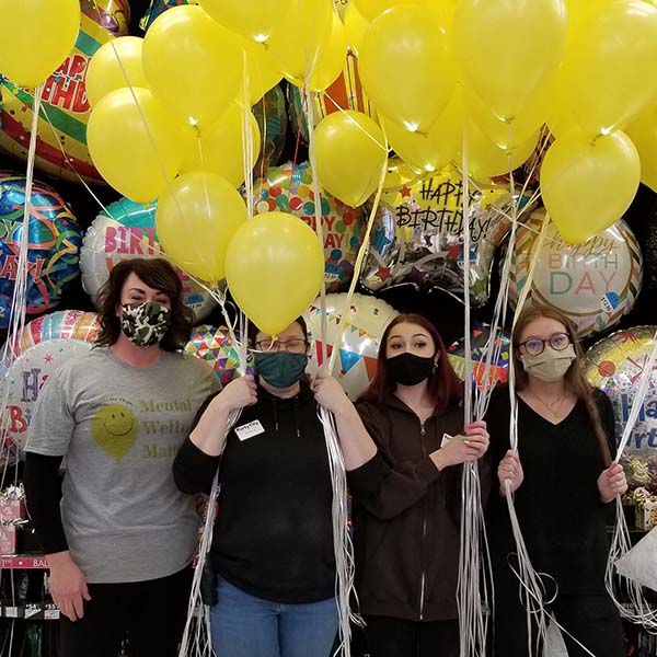 4 women holding yellow balloons